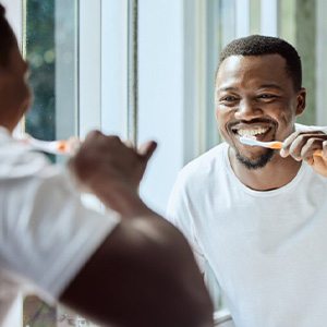 a man smiling and brushing his teeth