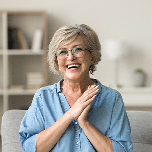 Senior woman with glasses smiling on couch at home