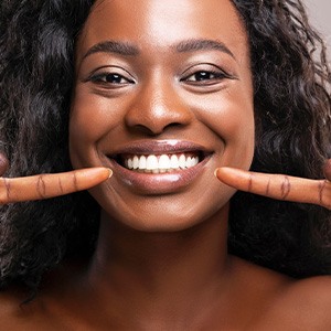 Woman pointing to her straighter set of teeth