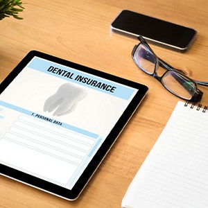 Dental insurance form on tablet next to desk supplies