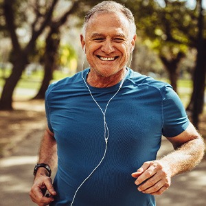 Senior man smiling while jogging outside