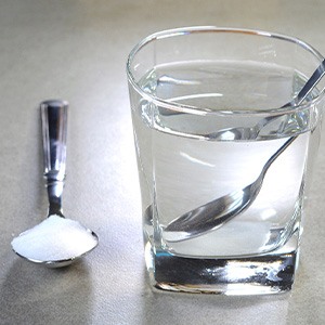 Spoon full of salt next to glass of water with mixing spoon