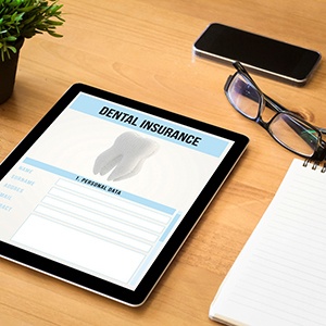 Dental insurance from on tablet next to notepad