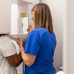 Dentist guiding patient to stand underneath a CBCT scanner