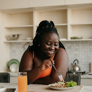 Woman smiling while eating healthy meal
