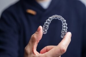 Dentist holding clear aligner. 